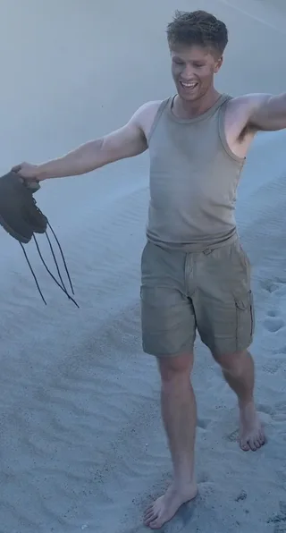 Robert Irwin Grinning Descalço em Areia em um Tank Top e Shorts