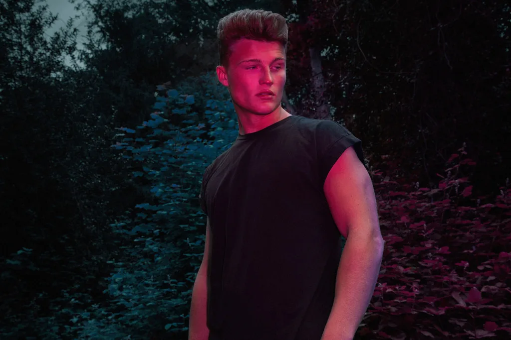 Zach Hartman 's mejslet torso glimter under fugtige skov lys, shirtless tillid på fuld visning