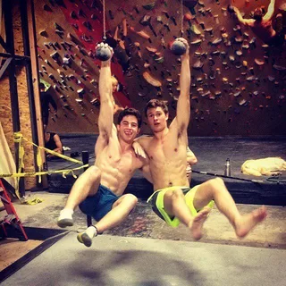 Ansel Elgort sem camisa no ar com amigo da academia, abdominais musculosos e shorts atléticos na academia de pedra