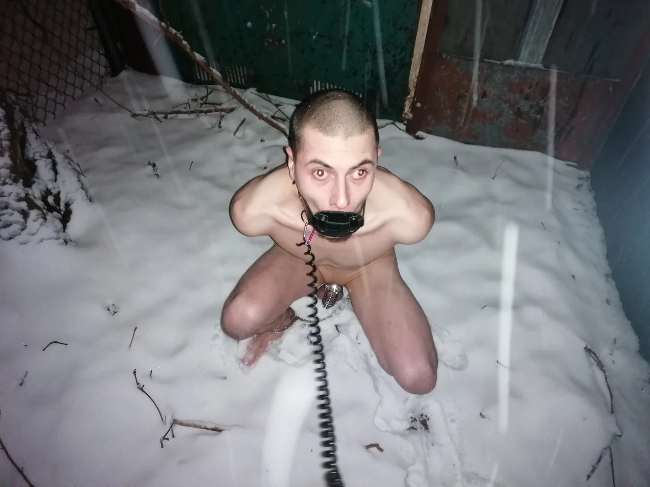Kinky fyr knæler nøgen i sne med telefon modtager gag og metal bold gag, intens øjenkontakt