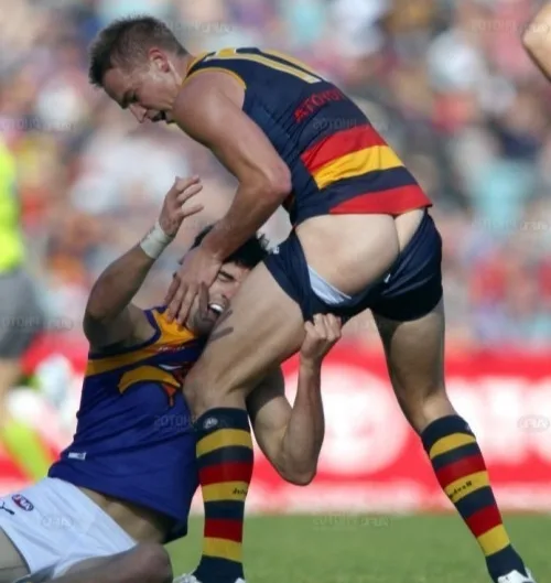 Hård rugby dreng i aktion, shorts ridning højt, røv på fuld visning mid- tackle