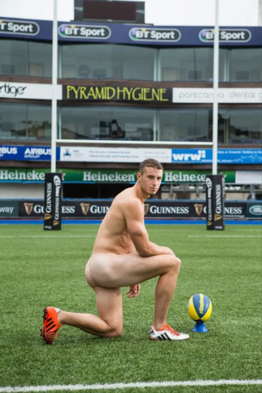 Sexy rugby-junge kniend nackt auf dem platz mit ball, schwanz versteckt, aber arsch auf dem display