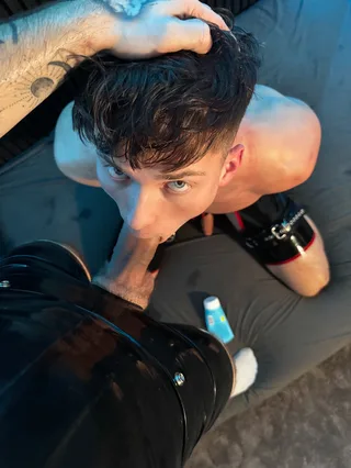 Cara esquisito de calça de látex preto fica com a cabeça presa enquanto chupa o pau duro