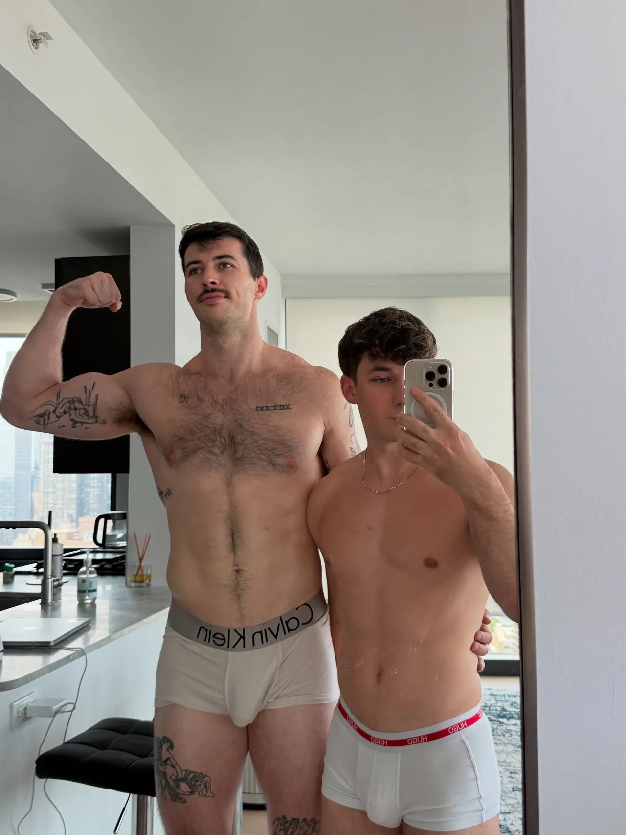 Two hot guys flexing shirtless in their underwear for a mirror selfie at home