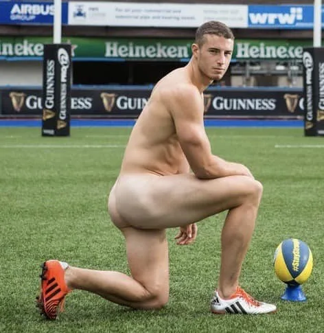 Sexy straight guy kneeling nude on rugby pitch with ball, ass on display