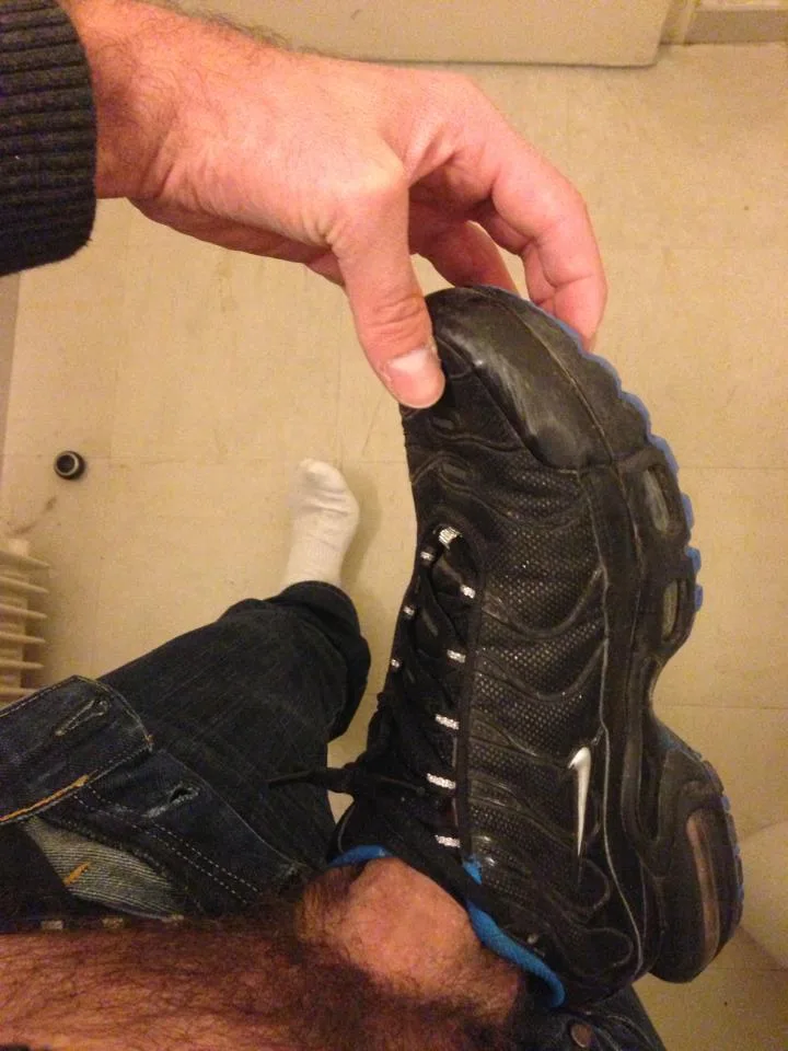 Fyren i jeans og sokker holder op sort sneaker, fod fetich fokus på tunge og snørebånd