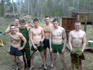 Caras de estilo militar sem camisa de short verde posam ao ar livre com ferramentas e sorrisos