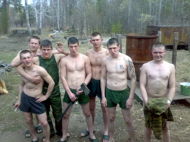 Skjult military- stil fyre i grønne shorts udgør udendørs med værktøjer og smil