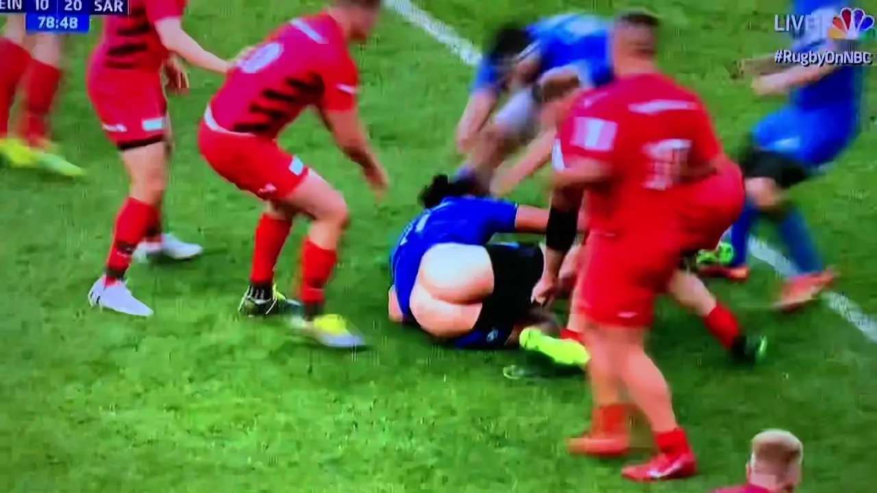 Sexy rugby lad in blue kit caught mid-tackle with ass cheek peeking out on grass