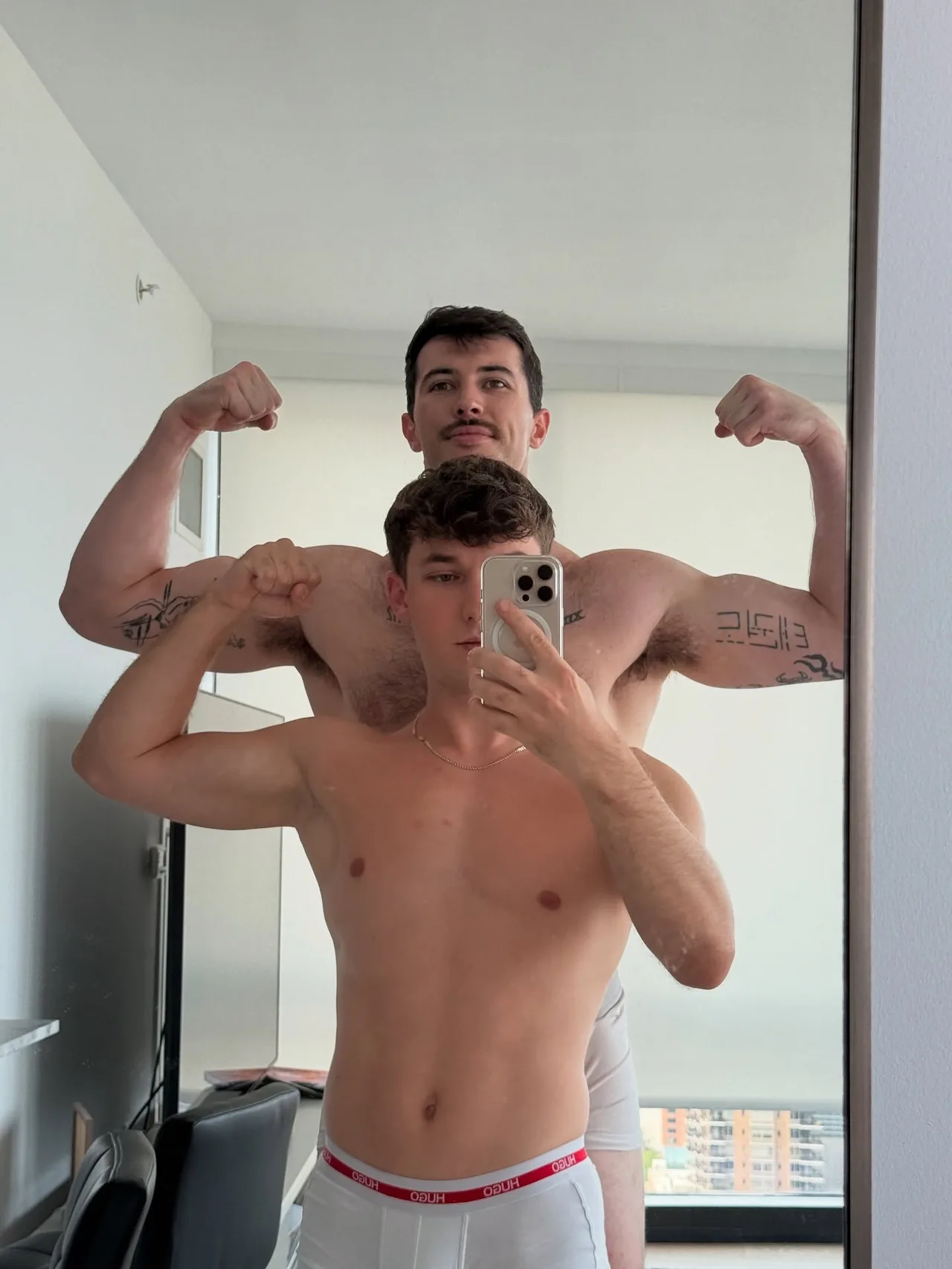 Two hot guys flexing shirtless in their underwear for a mirror selfie at home - photo 3