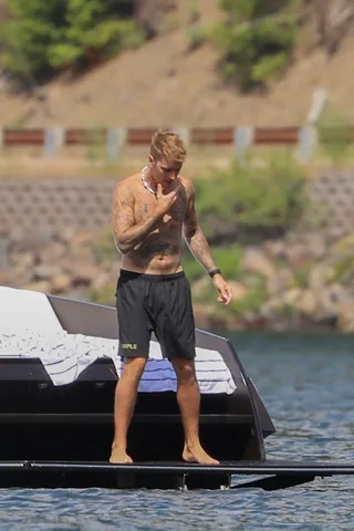 Justin Bieber sem camisa em um deck de iate sem pé e tatuado