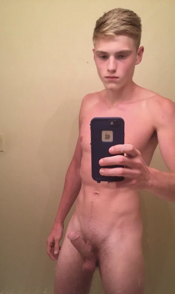 Blonde twink takes mirror selfie showing hard cock and hairy balls, totally nude in bathroom