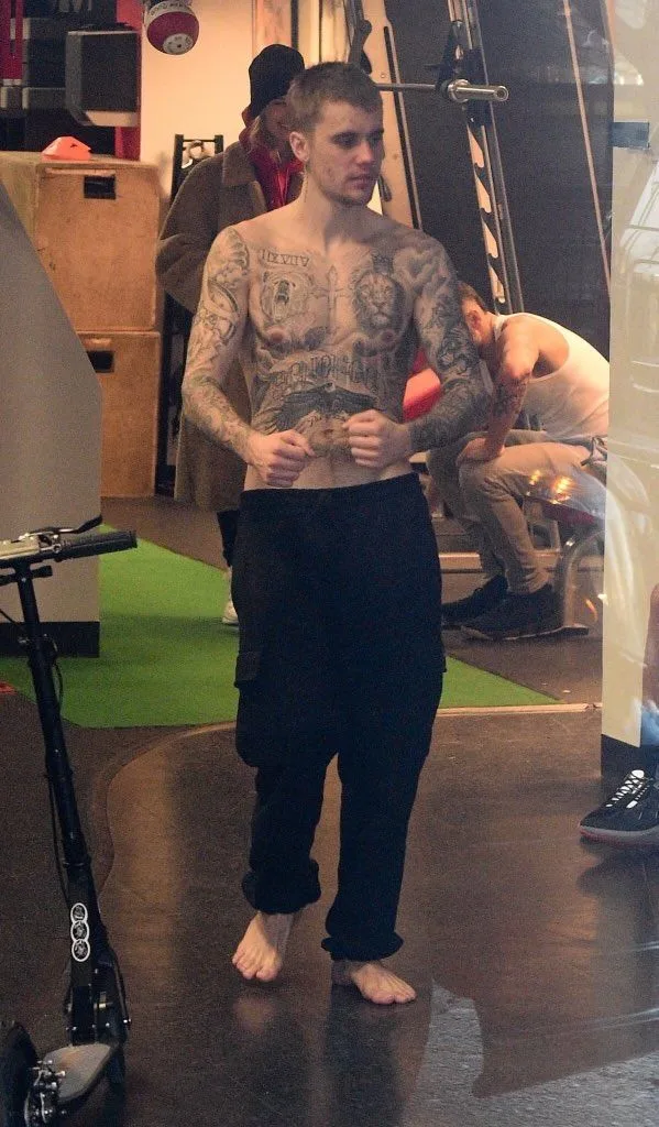 Justin Bieber hemdlos und barfuß in einem Fitnessstudio mit eingefärbtem Oberkörper