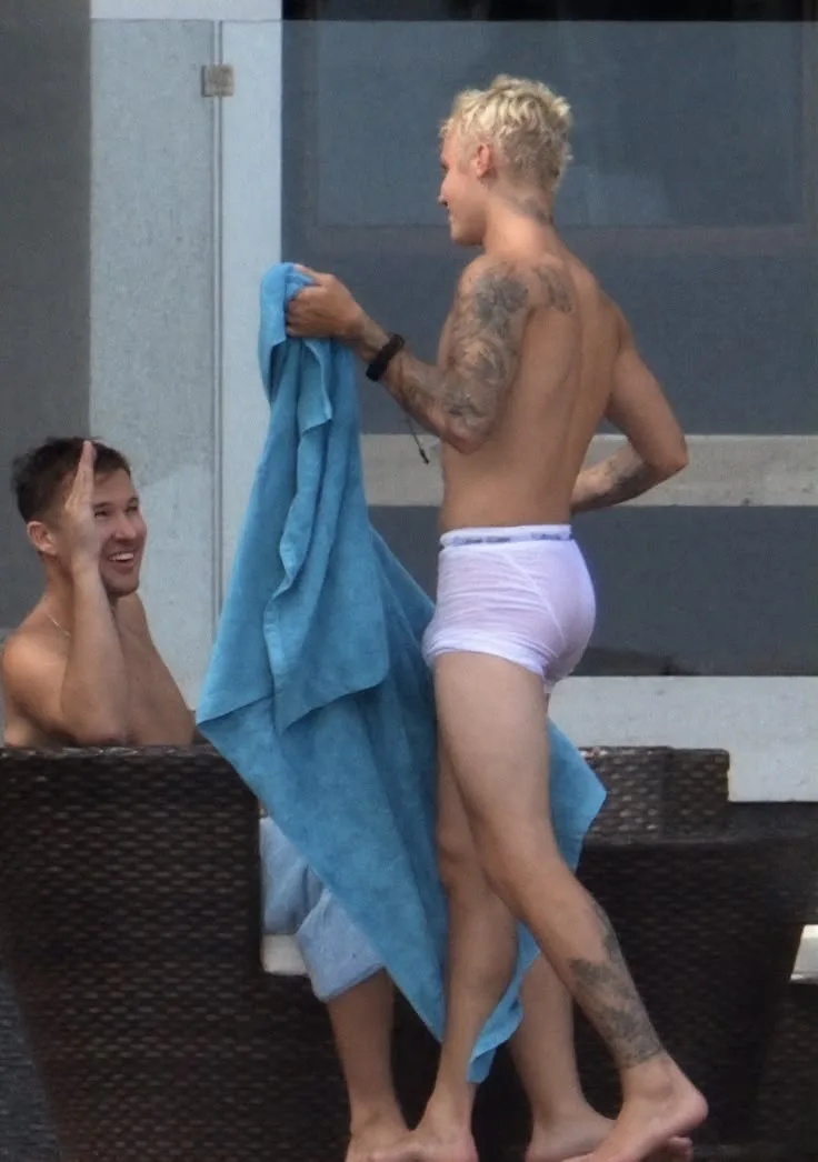 Justin Bieber hemdlos in weißen Slips hält ein blaues Handtuch am Pool
