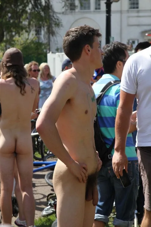 Rapaz sem camisa com pau na mão em reunião gay ao ar livre, iluminado e sem desculpas