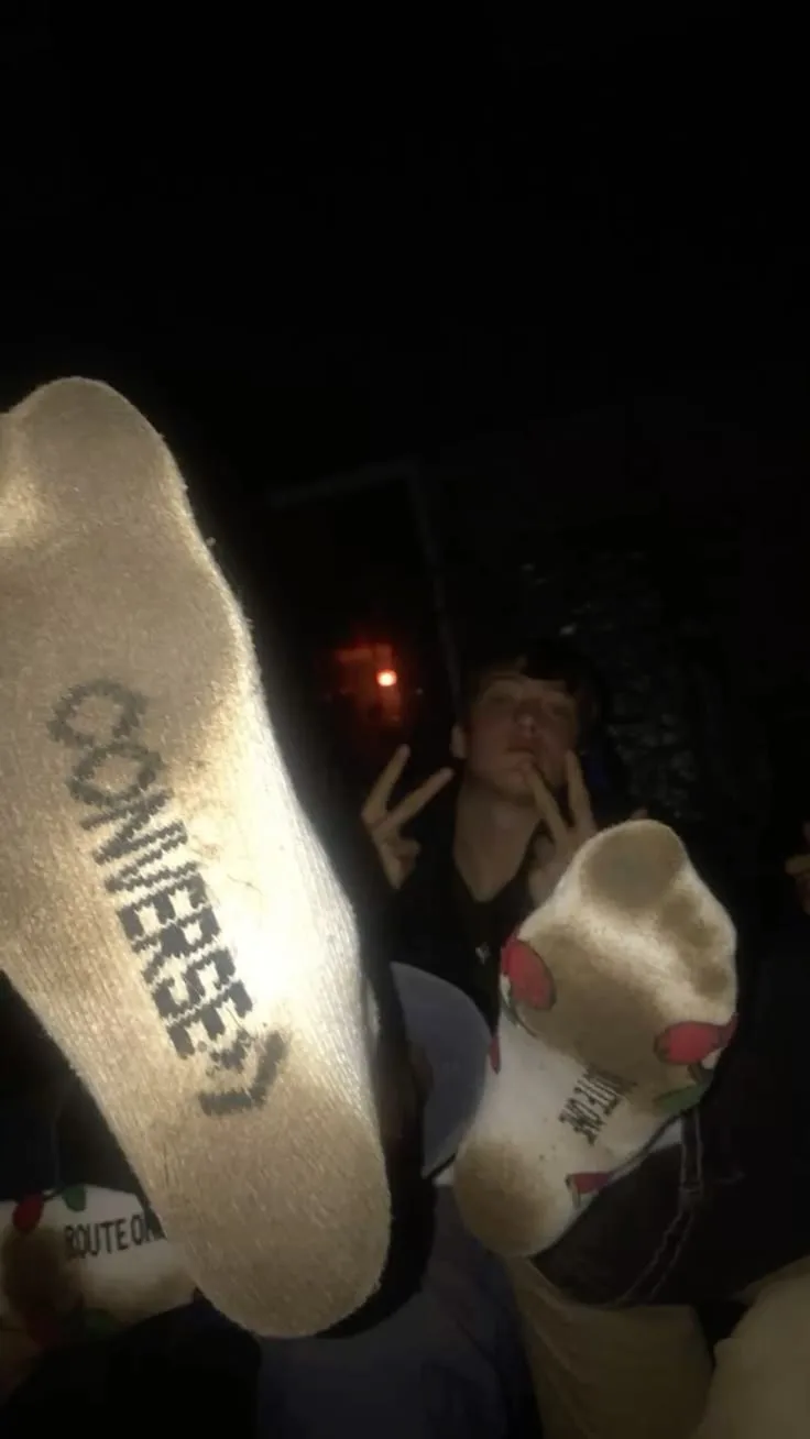 Facet migający skarpety konwersowe ze znakiem pokoju, stopy z bliska w ciemnym pokoju