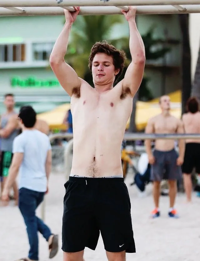 Skjult Ansel Elgort fletning abs på stranden pull- up bar, atletisk dreng i sorte shorts