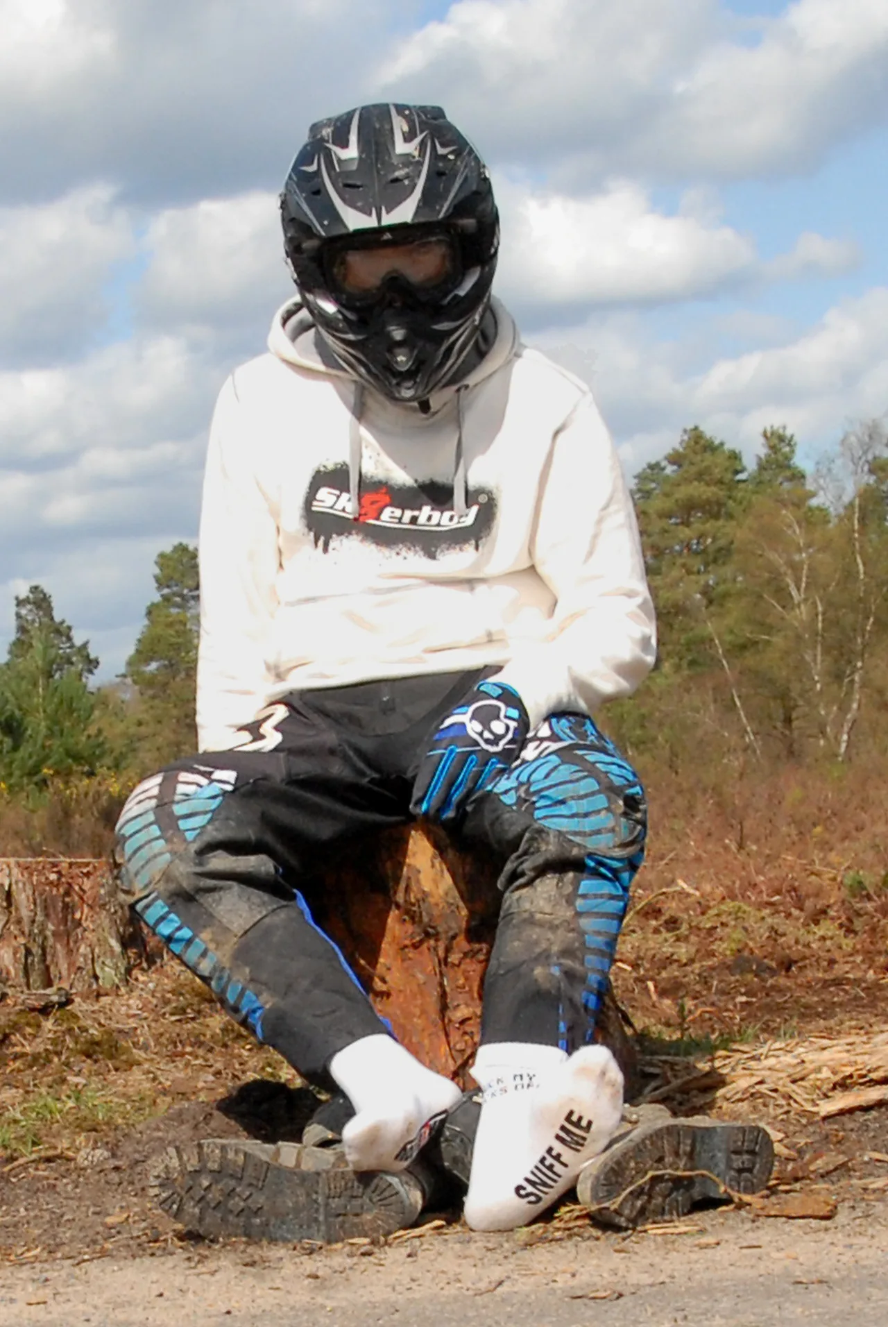 Brudny motocross chłopak w pełnym biegu siedzi na kikucie, białe skarpetki z "SNIFF ME" kpić z butów