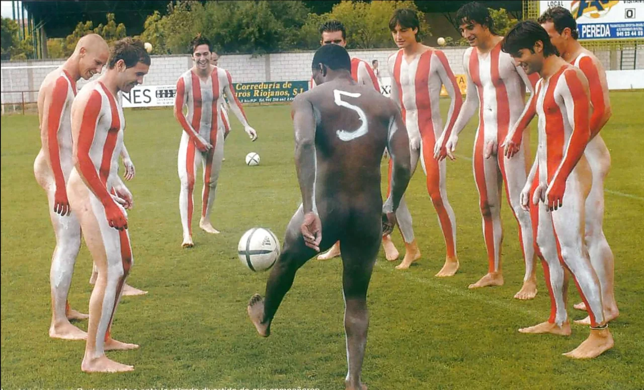 Fed exhibitionist drenge i rød-og-hvid krop maling udgør nøgen på en solrig bane med fodbold bolde
