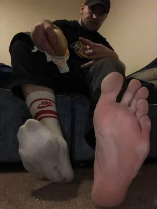 Guy in Nike socks chowing down with one bare foot front and center