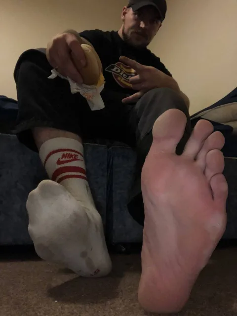 Guy in Nike socks chowing down with one bare foot front and center