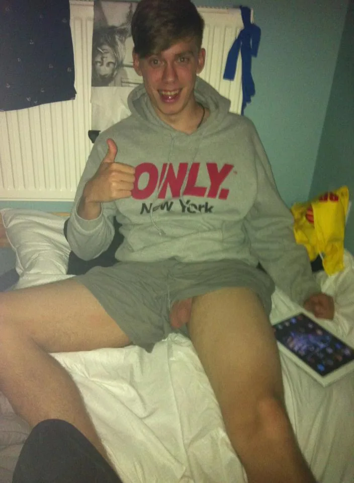 Cheeky lad in hoodie gives thumbs up while flashing hard cock on bed