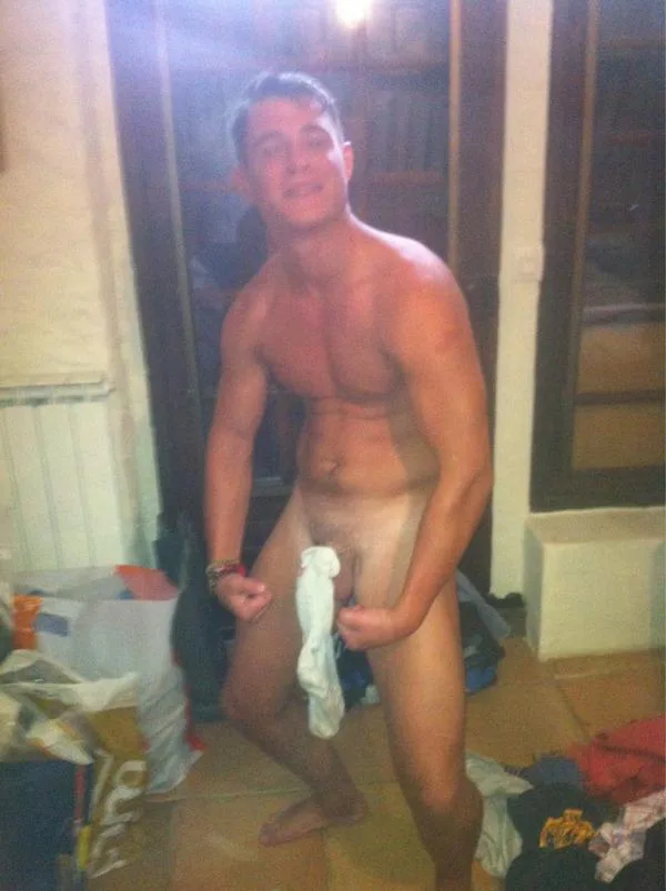 Ragazzo atletico sorridente in posa nudo con asciugamano, che mostra il suo cazzo duro e i testicoli