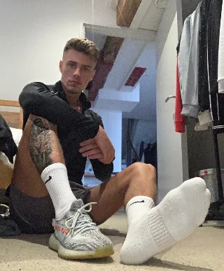 Sexy guy in socks and sneakers flexes feet for foot fetish fans