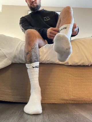 Bearded guy in Vans socks shows off hairy legs and tattooed calf while adjusting his sock