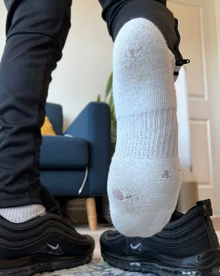 Dirty white socks and black Nikes: foot fetish guy flexing soles in living room