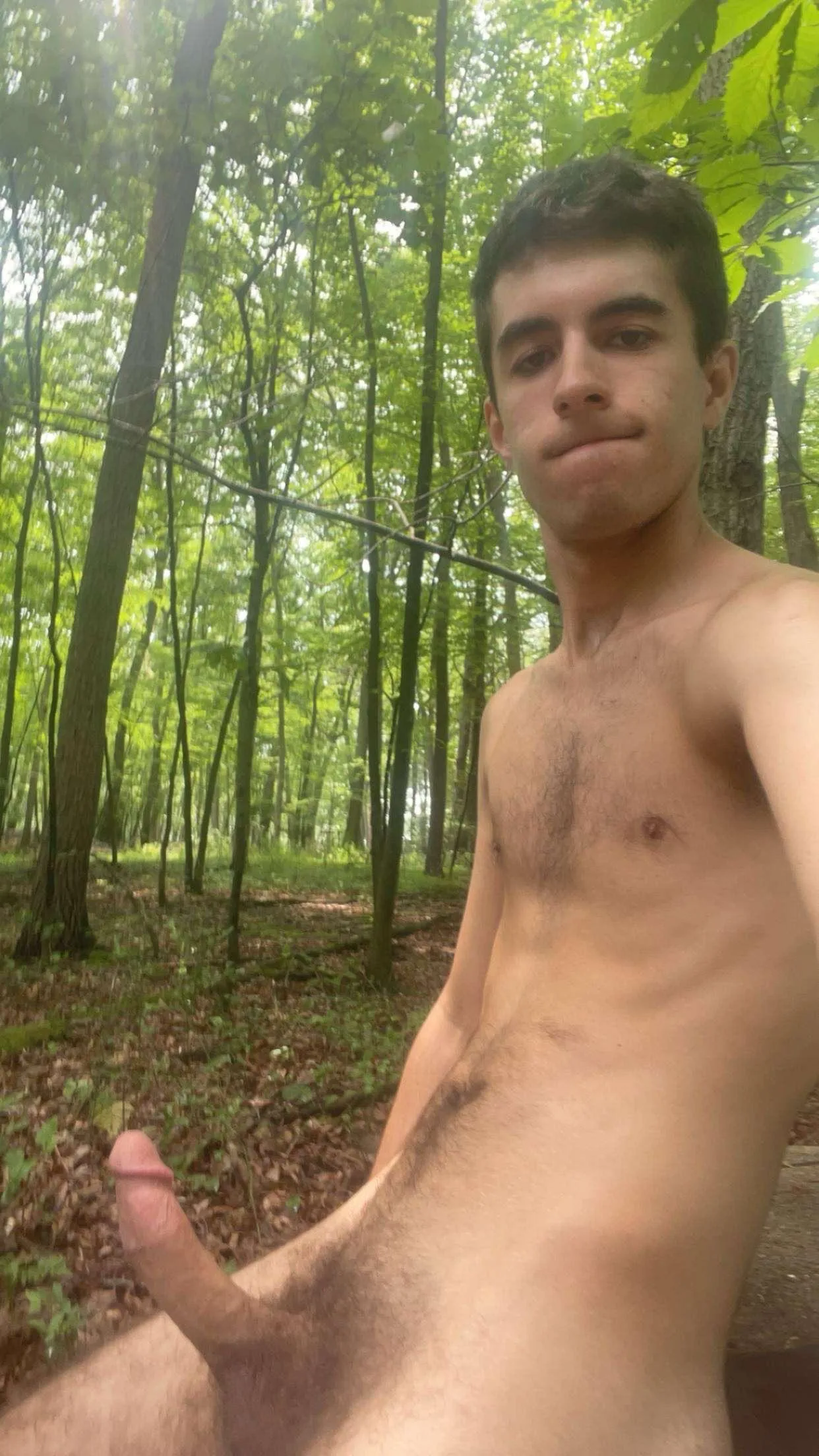 Homem com pênis ereto tirando selfie na floresta com exposição frontal completa