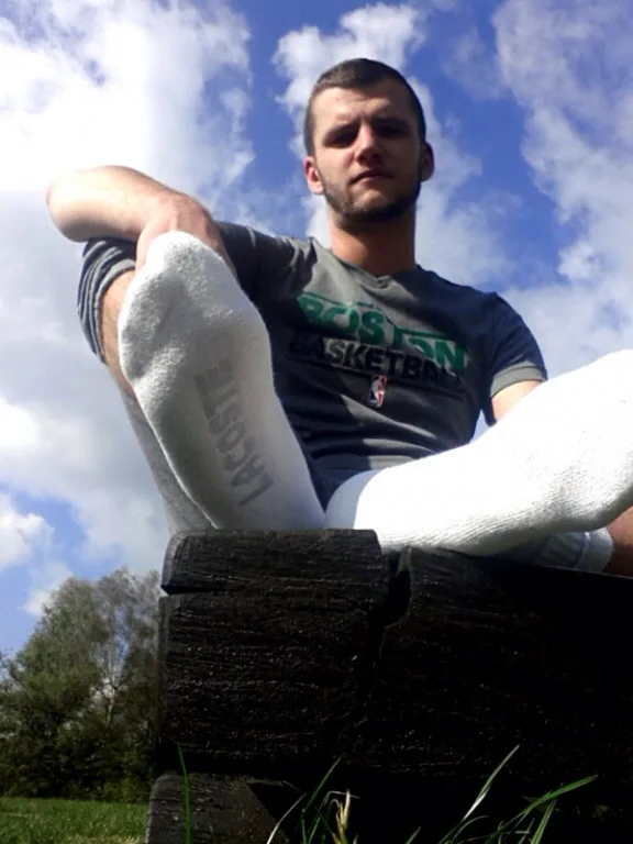 Scally lad in Boston tee and Lacoste socks lounging outdoors with legs spread wide