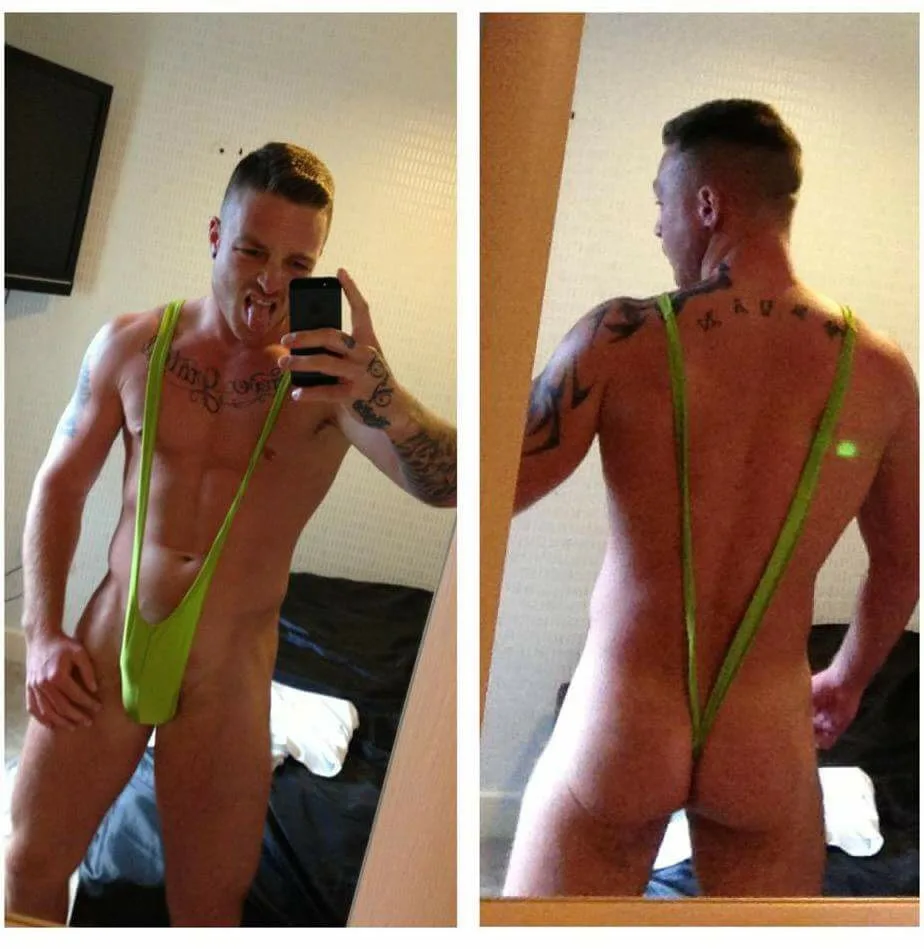 Garoto tatuado de sunga neon verde tira selfie provocante no espelho mostrando frente e bunda