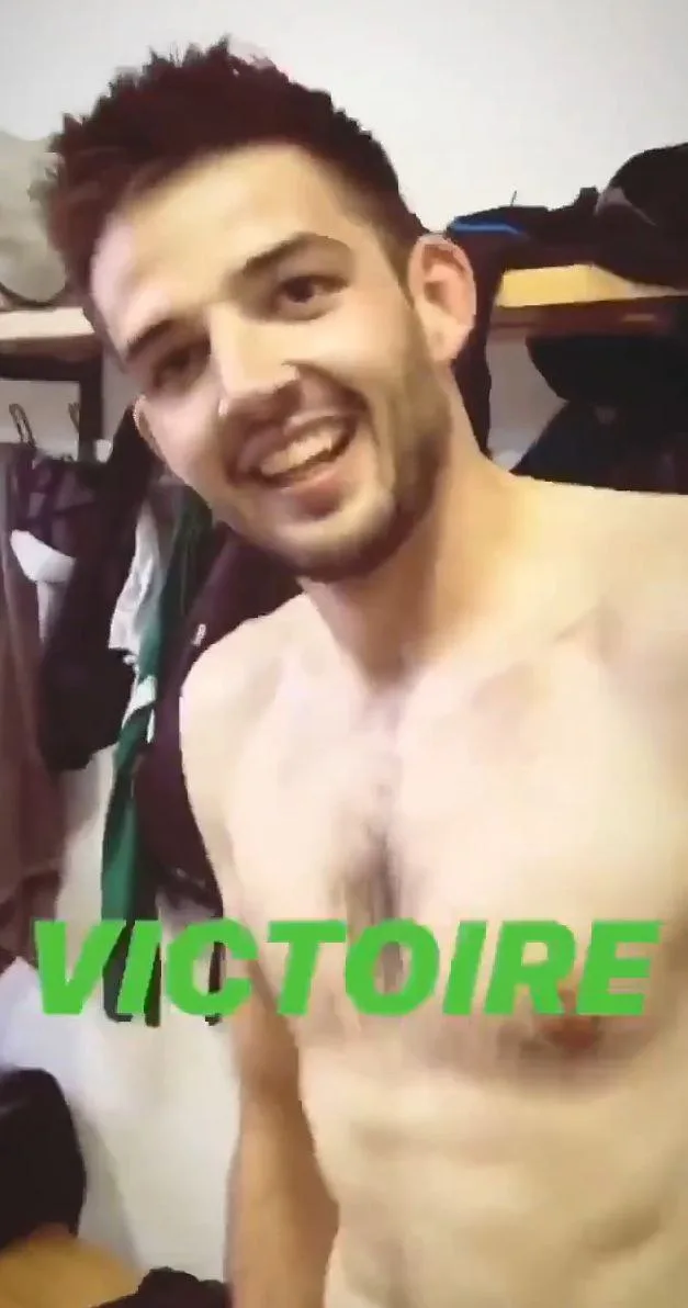Sorridente rapaz sem camisa sorri para a câmera com peito nu e verde texto VICTOIRE sobreposição