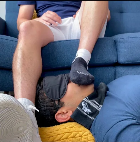 Foot-fetish guy in socks presses sole to blindfolded lad’s face on couch