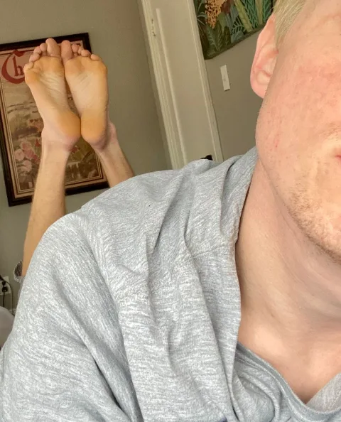 Lazy lad in grey tee shows off soles while lounging with feet up high