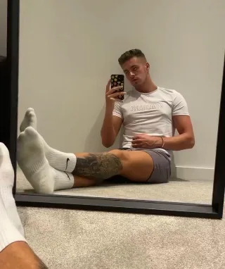Foot-fetish mirror selfie guy in white socks and shorts showing off his soles and tattooed calves