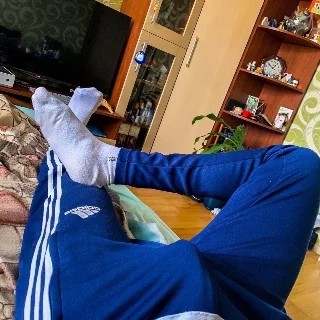 Lazy lad in blue Adidas tracksuit lounging with socked feet up, casual home vibe