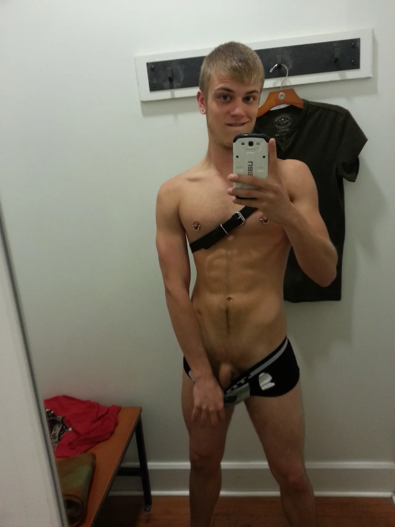 Garoto loiro tira selfie no espelho de cueca preta, exibindo o pau duro e os abdominais definidos