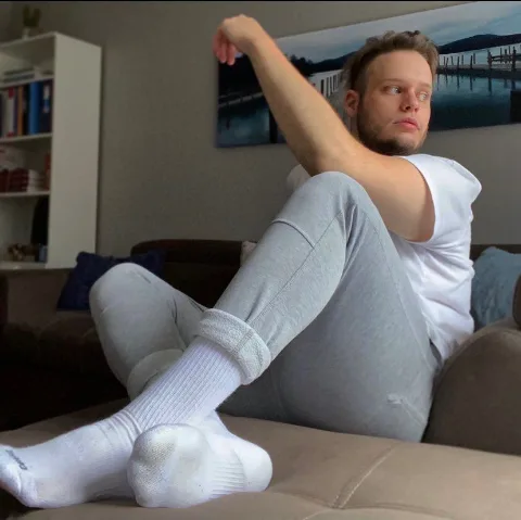 Lazy lad in white socks lounging on couch with feet up, casual home vibe