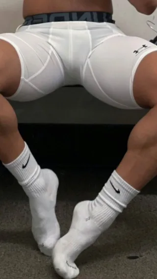 Muscular lad in white compression shorts and Nike socks flexes his soles for foot fetish fans