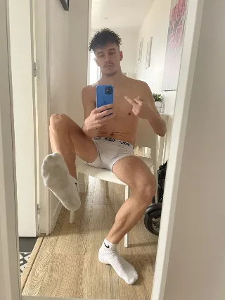 Shirtless lad in white briefs and socks snaps mirror selfie, one foot kicked up for foot fetish fans