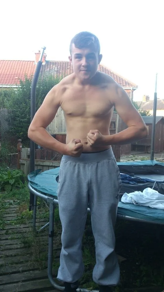 Skjult scally dreng flexing bare brystet i grå tracksuit bunde udendørs
