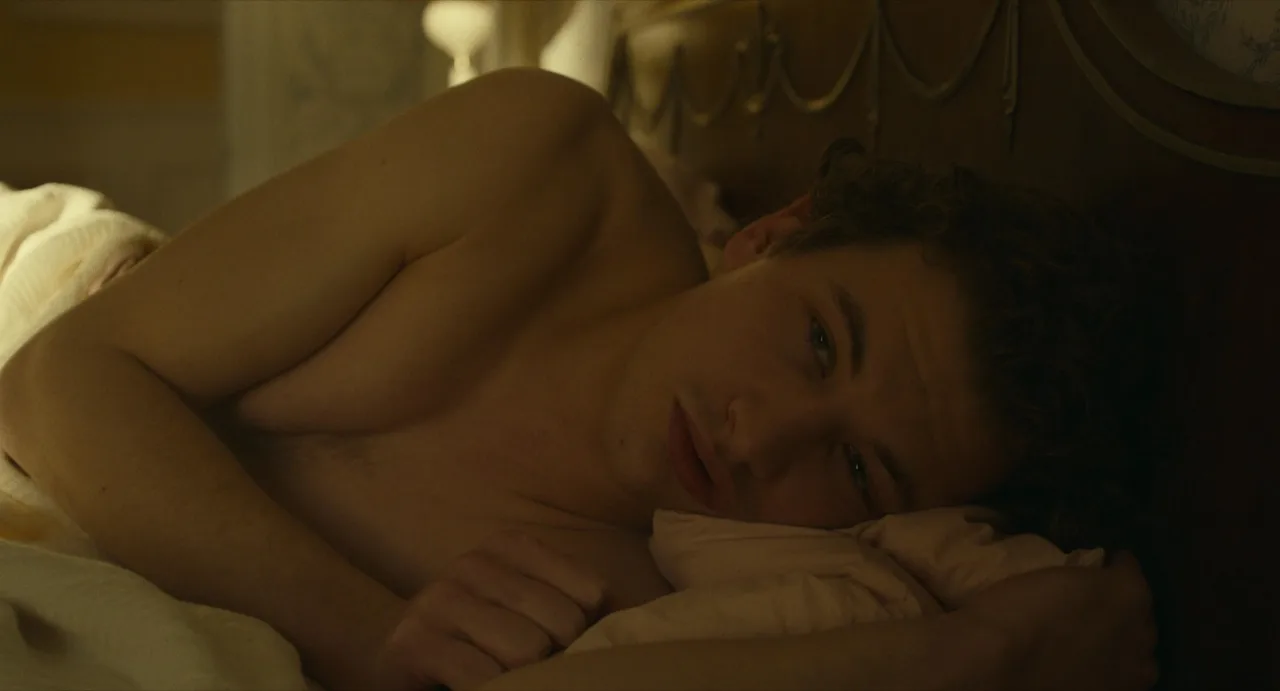 Shirtloser Tye Sheridan, entspannt im Bett mit zerzausten Locken und lässigem Lächeln