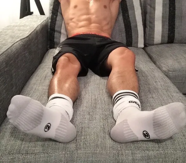 Muskulær dreng lounging på sofaen i sokker, abs på displayet, fødder foran og center for fod fetich fans