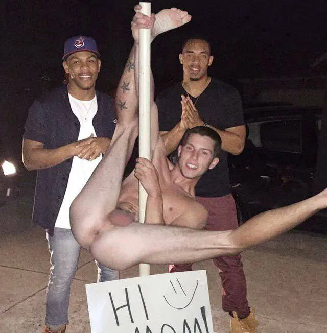 Naughty lad upside down on pole with mates grinning behind, bare ass on full display