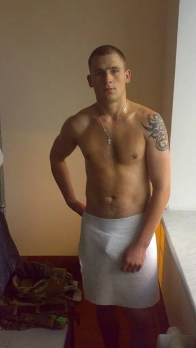Garoto hétero quente com toalha, braço tatuado e abdômen definido posando com confiança