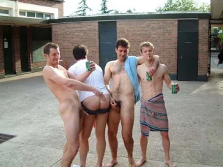 Four lads messing around shirtless outdoors with one flashing his ass and another holding a towel