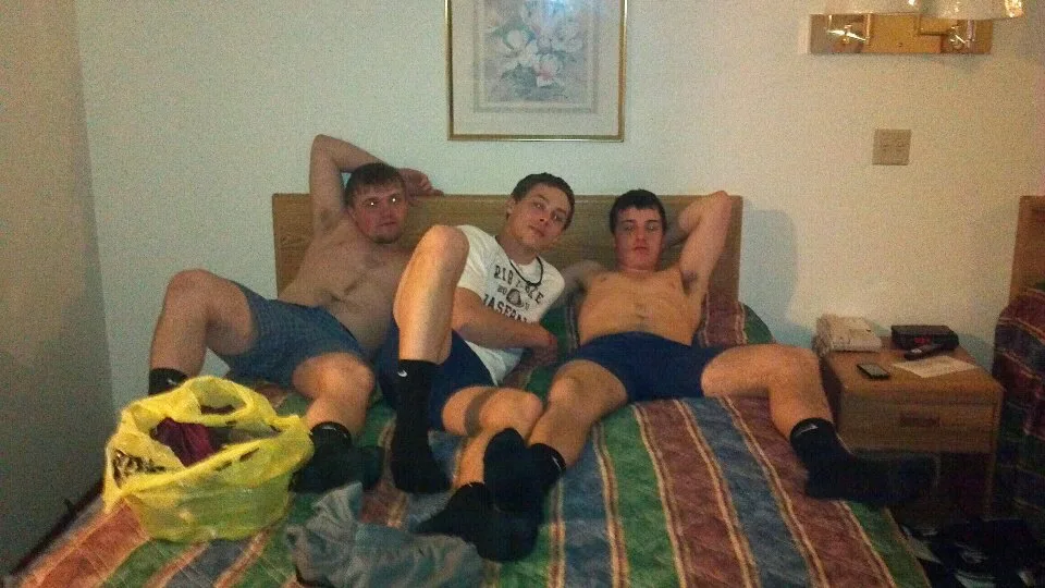 Tre uhyggelige drenge lounging shorts og sokker på en seng, afslappet og kæphøj