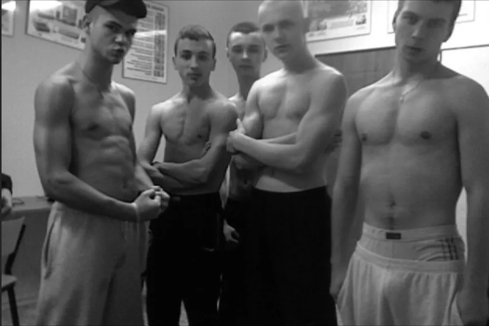 Pięciu chłopców bez koszuli w szortach i dresach pozujących bez klatek piersiowych z poważnymi spojrzeniami